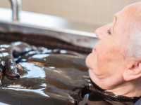 Senior woman enjoying mud bath alternative therapy
