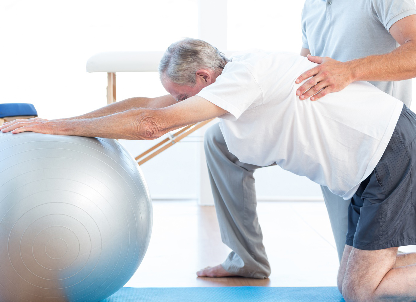 Physiotherapist helping man with exercise ball