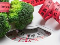 Broccoli with measuring tape on weight scale. Dieting