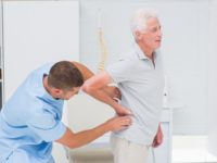Physiotherapist giving back massage to senior man