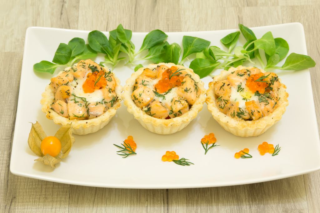 Salmon baked tartlet with mozzarella on a white plate Salmon baked tartlet with mozzarella on a white plate