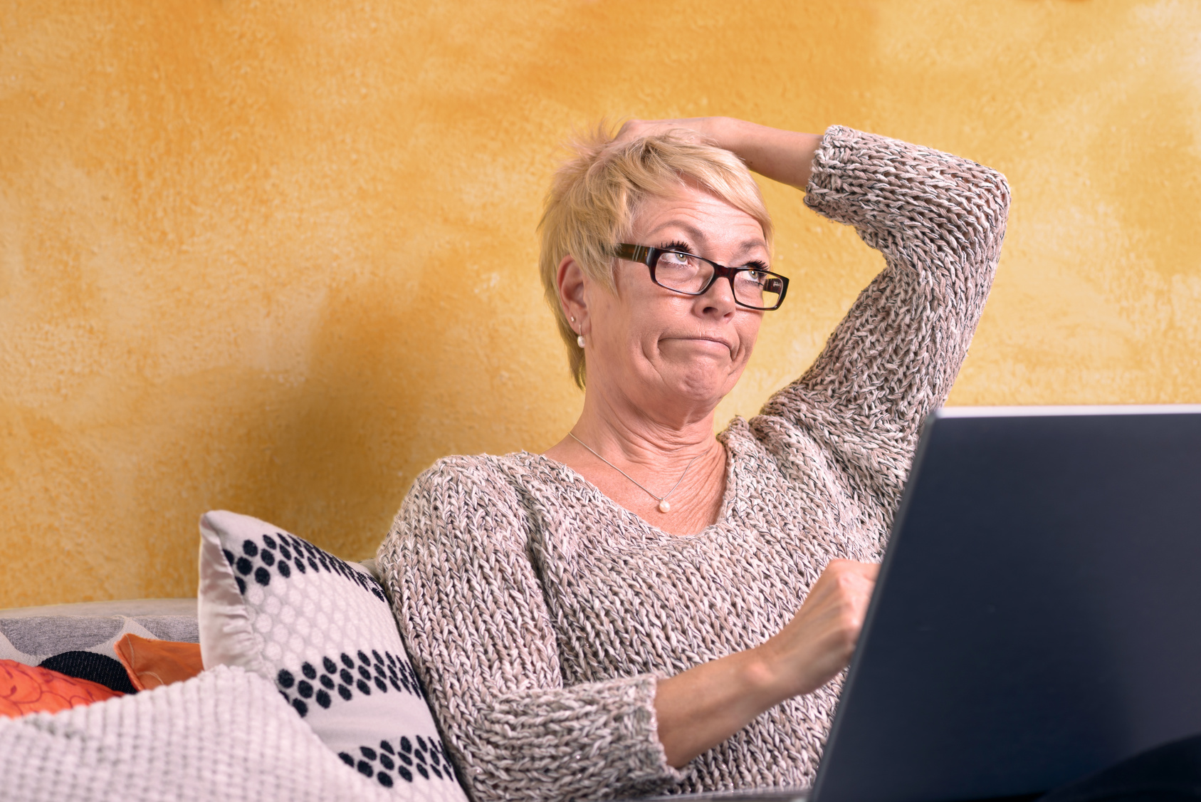 Aktive Rentnerin schaut besorgt auf Ihr Laptop